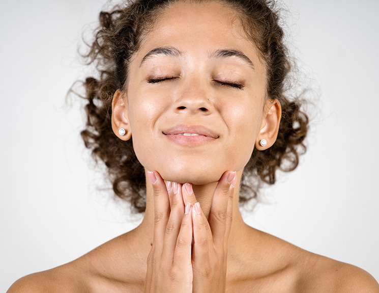 Cheerful curly woman touching chin 